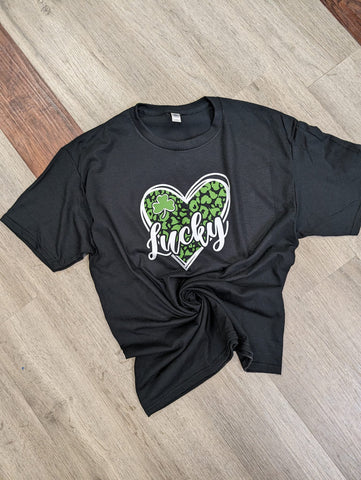 St Patricks Day Tee shirt for women that is a white heart with green leopard print and says Lucky in the middle. 